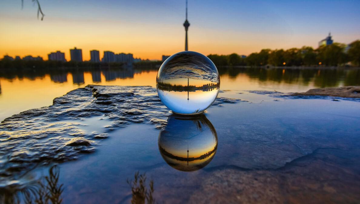 Skyline einer Stadt durch eine Glaskugel im Sonnenuntergang fotografiert