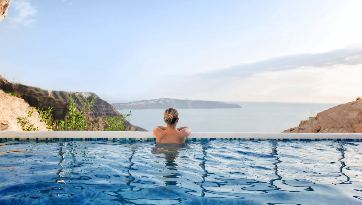 Rückansicht einer Frau in einem Infinitypool mit Blick aufs Meer