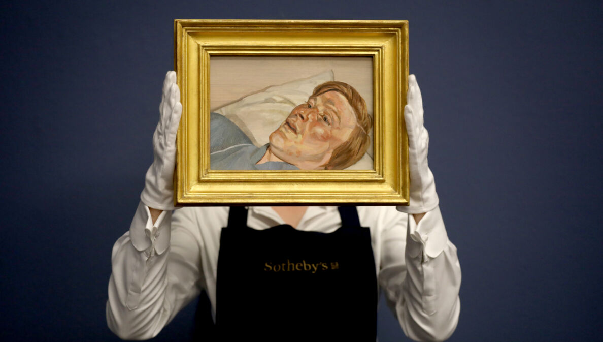 Eine Mitarbeiterin von Sotheby’s hält mit weißen Handschuhen ein kleines Gemälde von Lucian Freud in einem goldenen Rahmen hoch