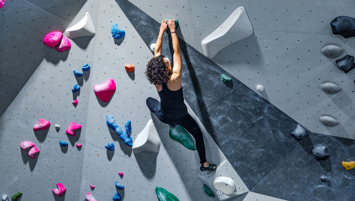 Eine Frau an einer künstlichen Kletterwand