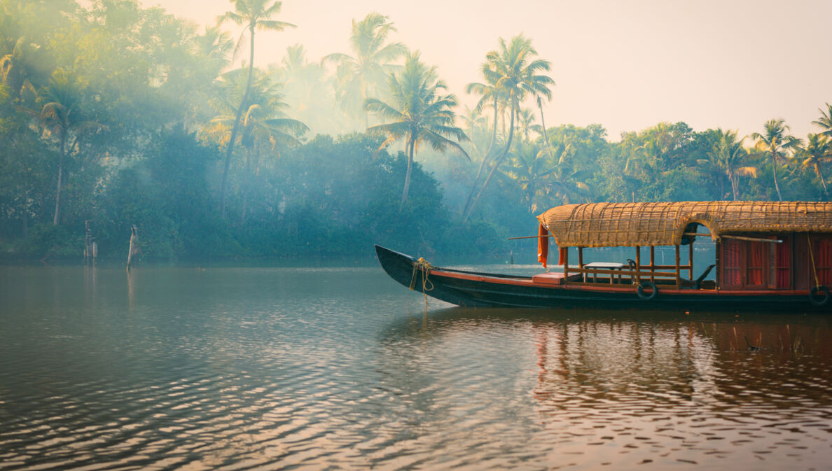 Ein traditionelles Hausboot bei Sonnenuntergang in den Backwaters im Palmenduschungel von Kerala