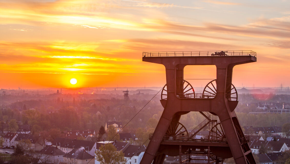 Blick auf Doppelbock-Fördergerüst vom Dach der Kohlenwäsche des UNESCO-Welterbes Zollverein beim Sonnenaufgang