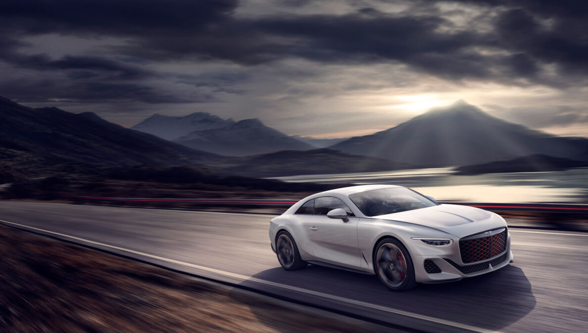 Weißes Auto von Bentley auf einer Straße, im Hintergrund Berge und Wolken