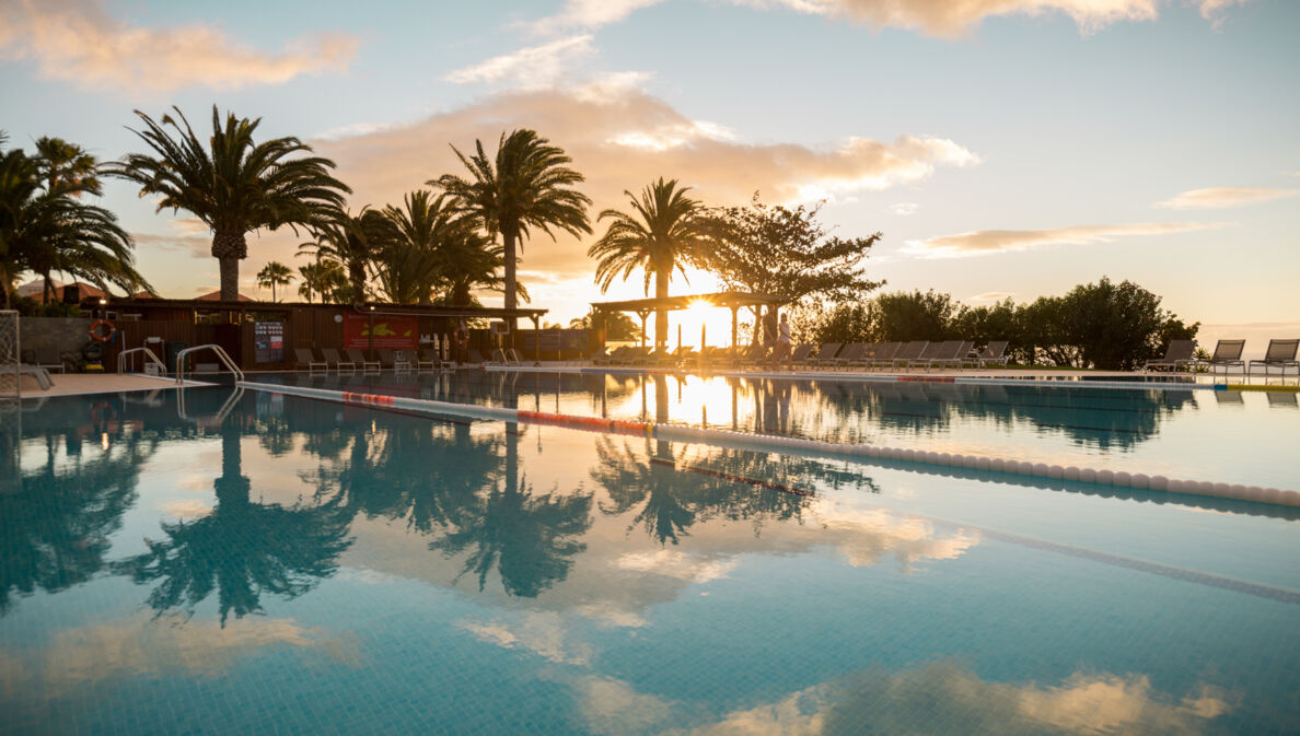 Ein großer Außenpool in einer Hotelanlage am Meer bei Sonnenuntergang