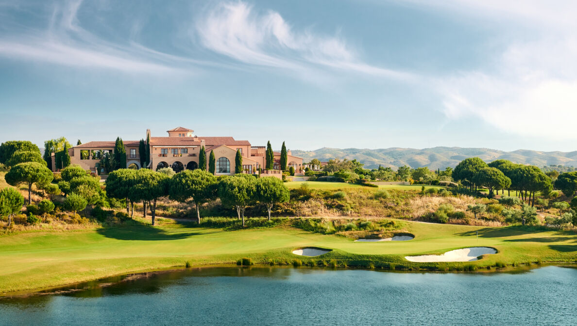 Ein Klubhaus auf einem Golfplatz mit Bäumen und einem See