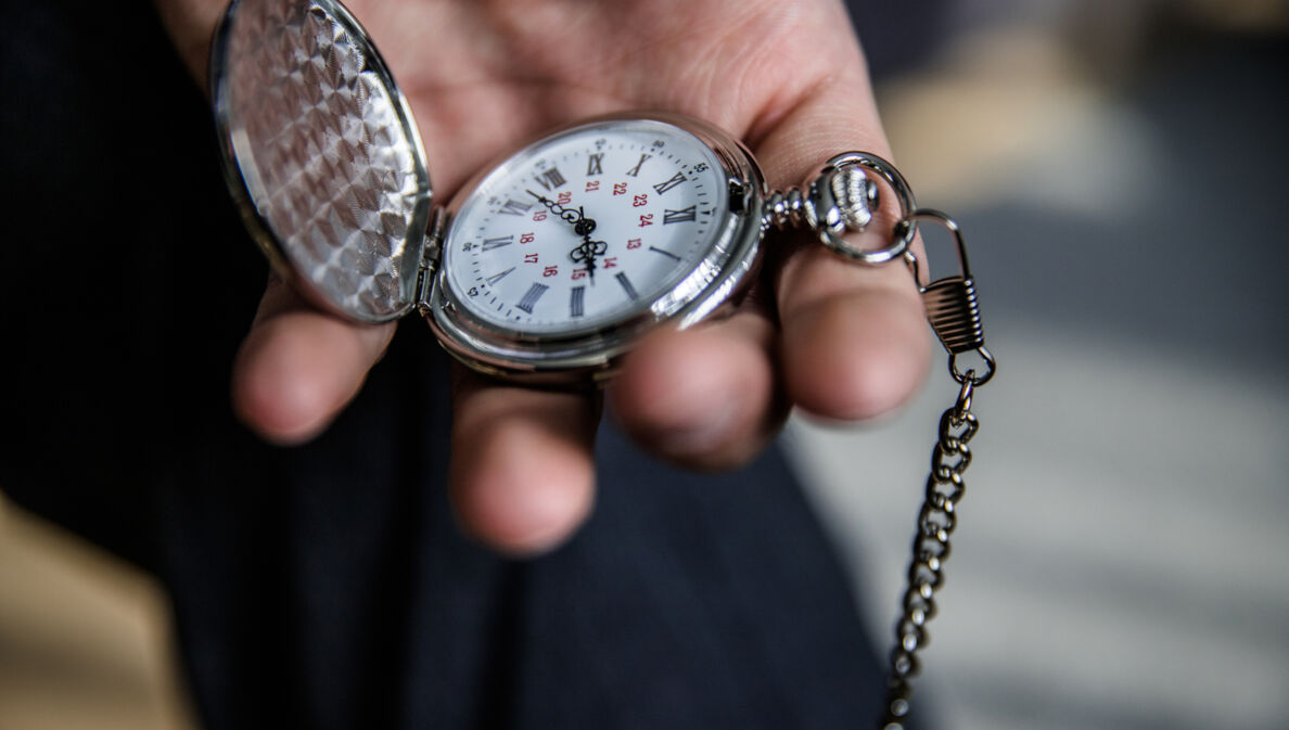 Eine Person hält eine aufgeklappte Taschenuhr in der Hand