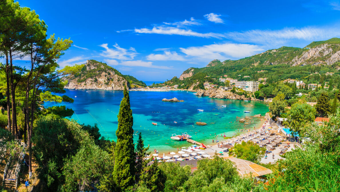 Blick über den Strand von Paleokastritsa mit türkisem Wasser und grüner Umgebung