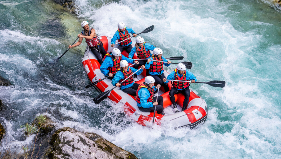 Acht Personen beim Wildwasser-Rafting in einem Schlauchboot