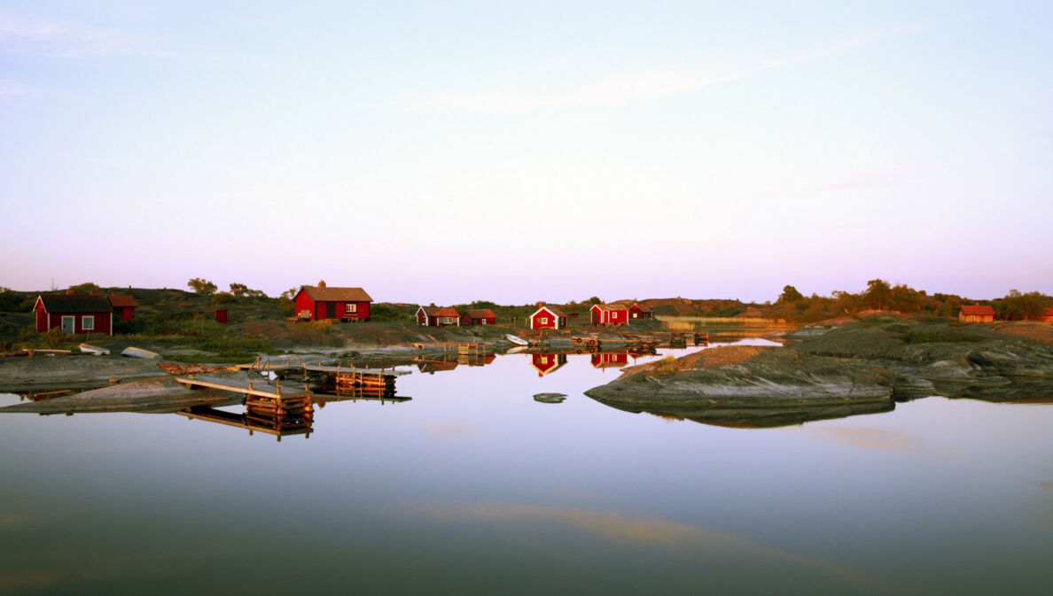 Blick auf rote Holzhäuser auf einer Insel in Schweden