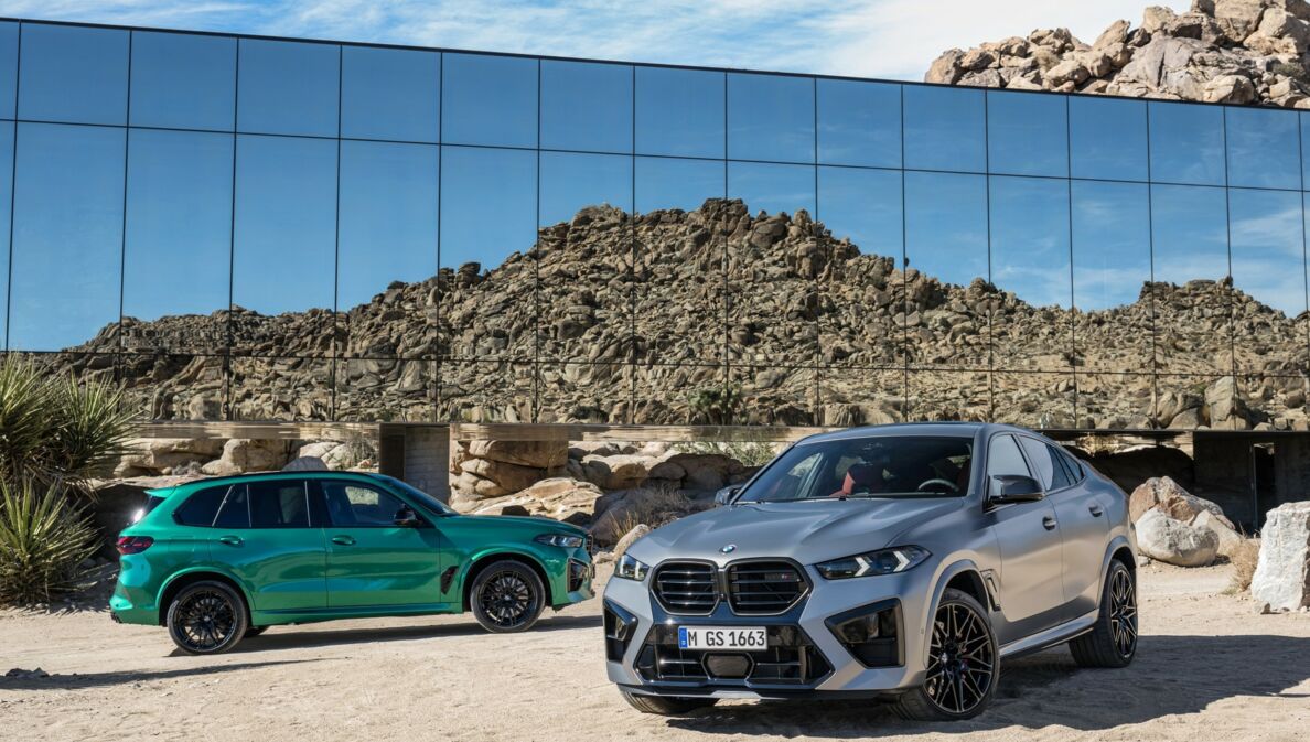 Ein silberner und ein grüner BMW-SUV in einer Landschaft aus Stein und Sand