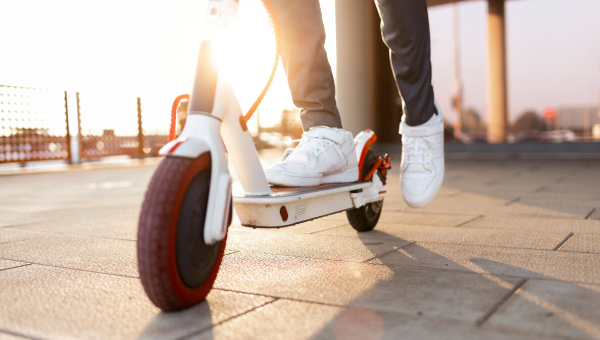 Nachaufnahme eines Rollers, auf dem ein Mann mit weißen Turnschuhen steht, Symbolbild