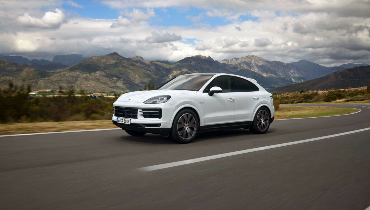 Ein weißer Porsche Cayenne auf einer Straße, im Hintergrund Berge