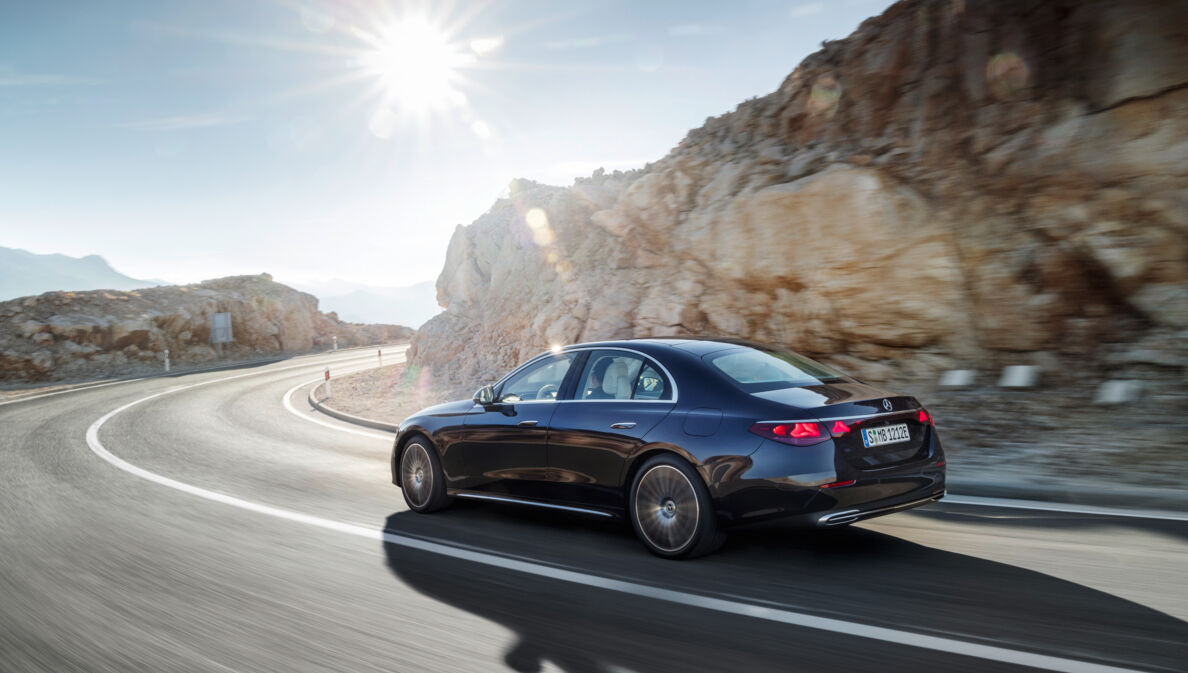 Ein schwarzer Mercedes seitlich von hinten in einer Kurve auf einer Bergstraße