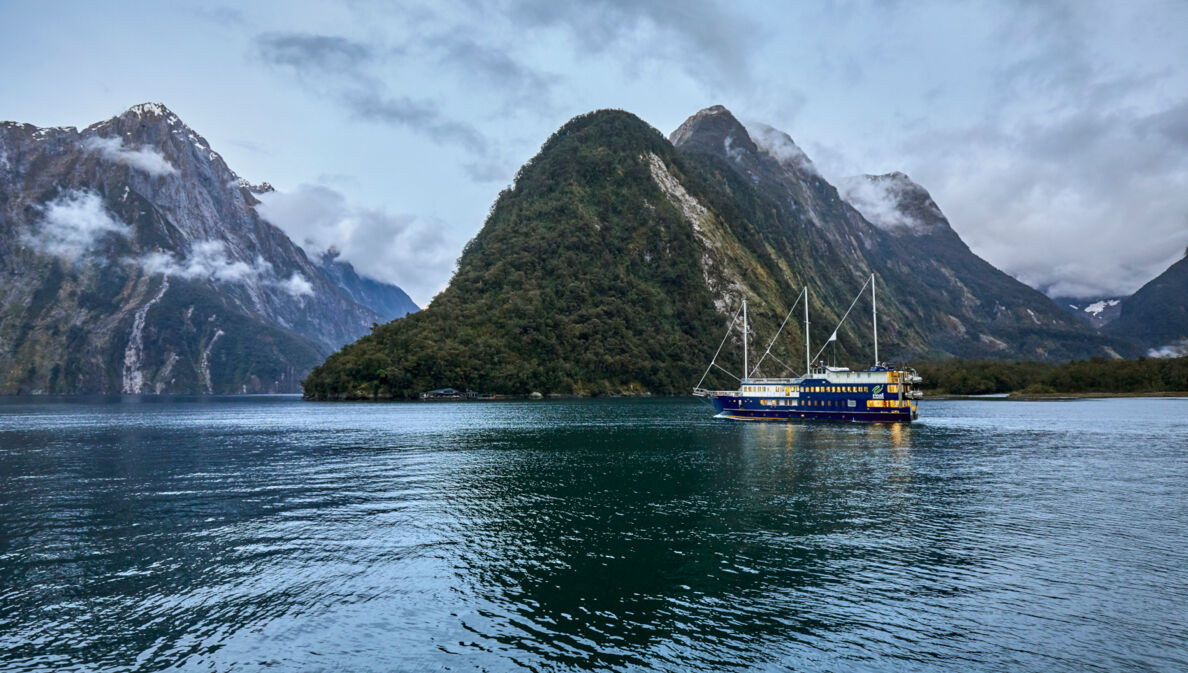 Ein Schiff vor einem Bergmassiv in Neuseeland