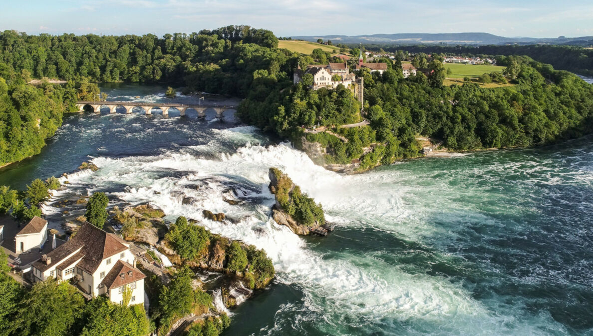 Luftaufnahme des Rheinfalls mit Schloss Laufen inmitten bewaldeter Natur