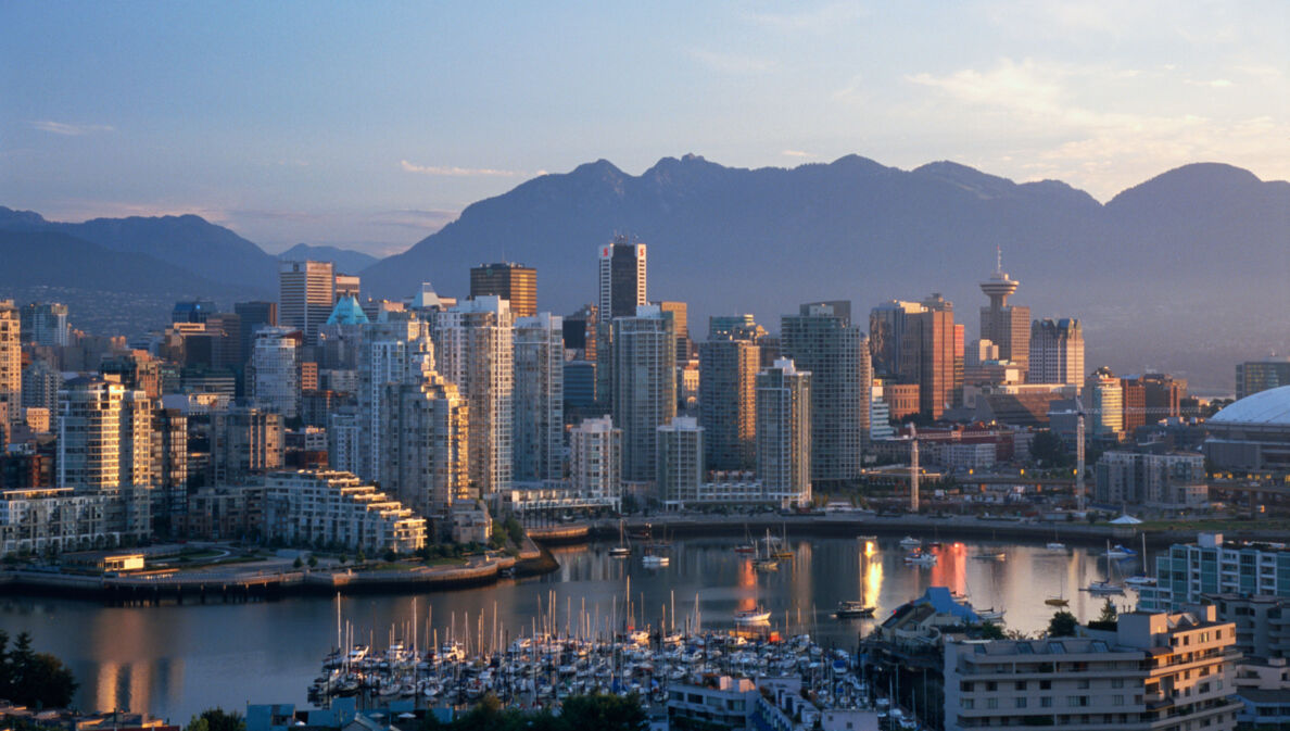 Skyline von Vancouver vor Bergpanorama in der Abenddämmerung.