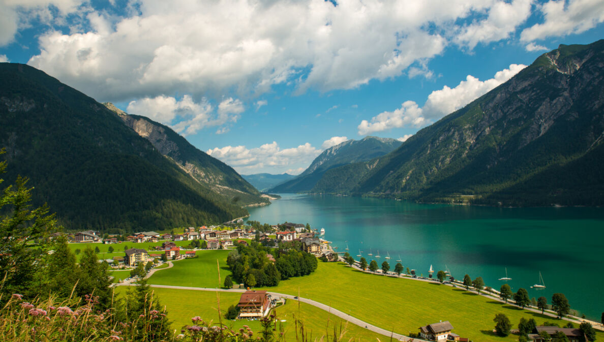 Ein türkisfarbener See zwischen Bergen und einem kleinen Dorf