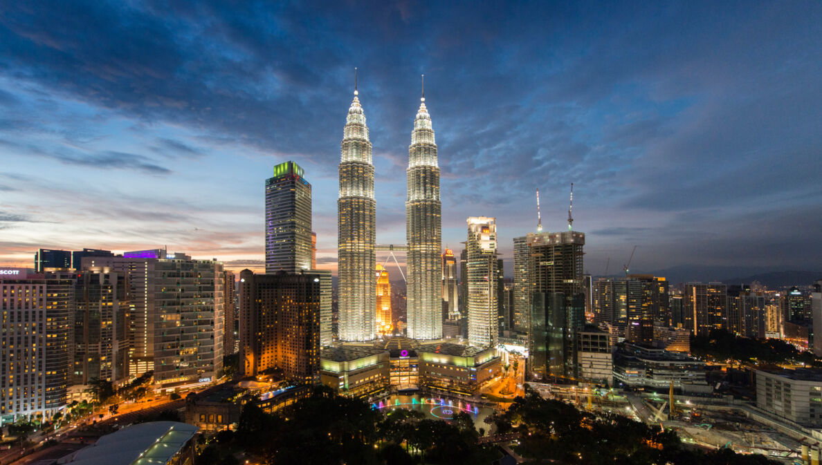 Nachtaufnahme der erleuchteten Skyline der City von Kuala Lumpur mit den Petrona Twin Towers im Mittelpunkt.