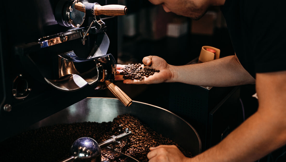 Ein Mann kontrolliert die Röstung von Kaffeebohnen