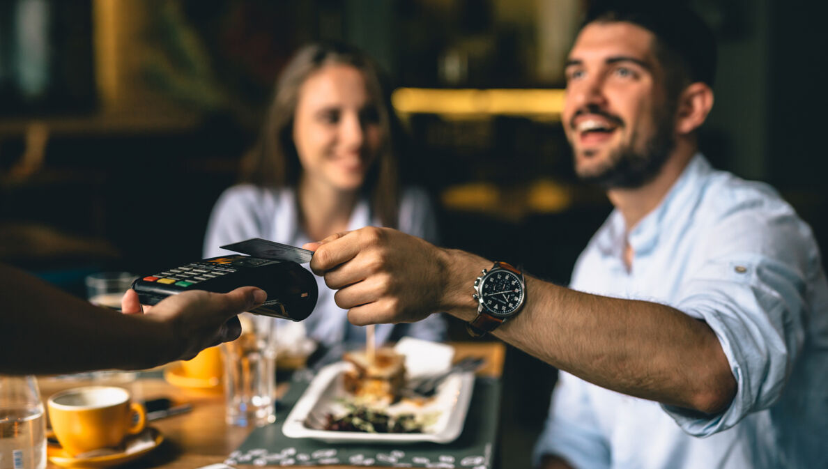 Junges Paar im Restaurant bezahlt mit Kreditkarte