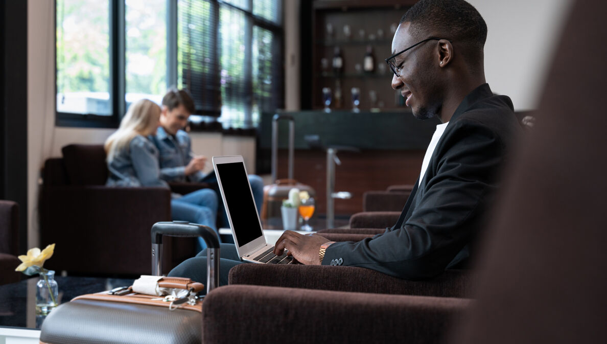 Geschäftsmann arbeitet in Hotellobby am Laptop