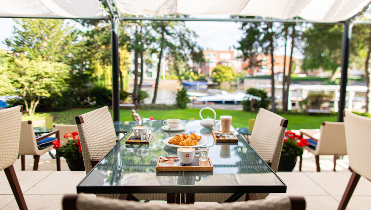 Frühstück auf einem Tisch auf einer Hotelterrasse an einem Kanal.