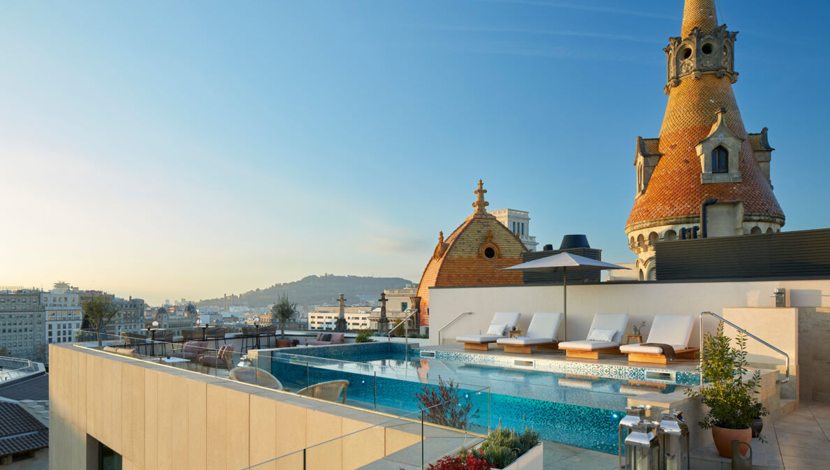 Hotelpool mit Sonnenliegen auf einer modernen Dachterrasse im Stadtzentrum.