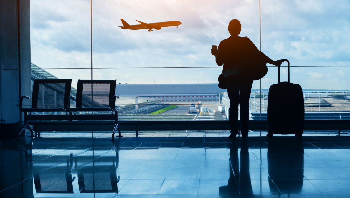 Silhouette einer Frau am Flughafen, die den Start eines Flugzeugs beobachtet.