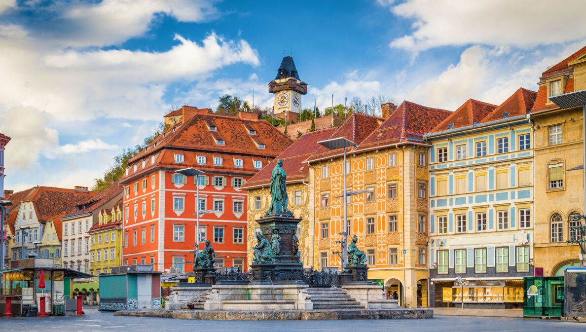 Marktplatz mit Brunnen vor bunter Häuserfassade in der Altstadt von Graz.