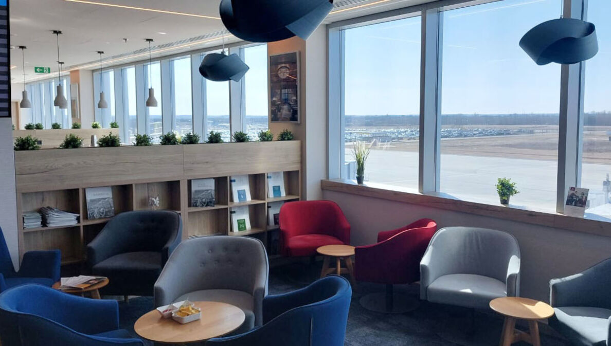 Flughafen-Lounge mit Sitzgruppen und Blick aufs Rollfeld.