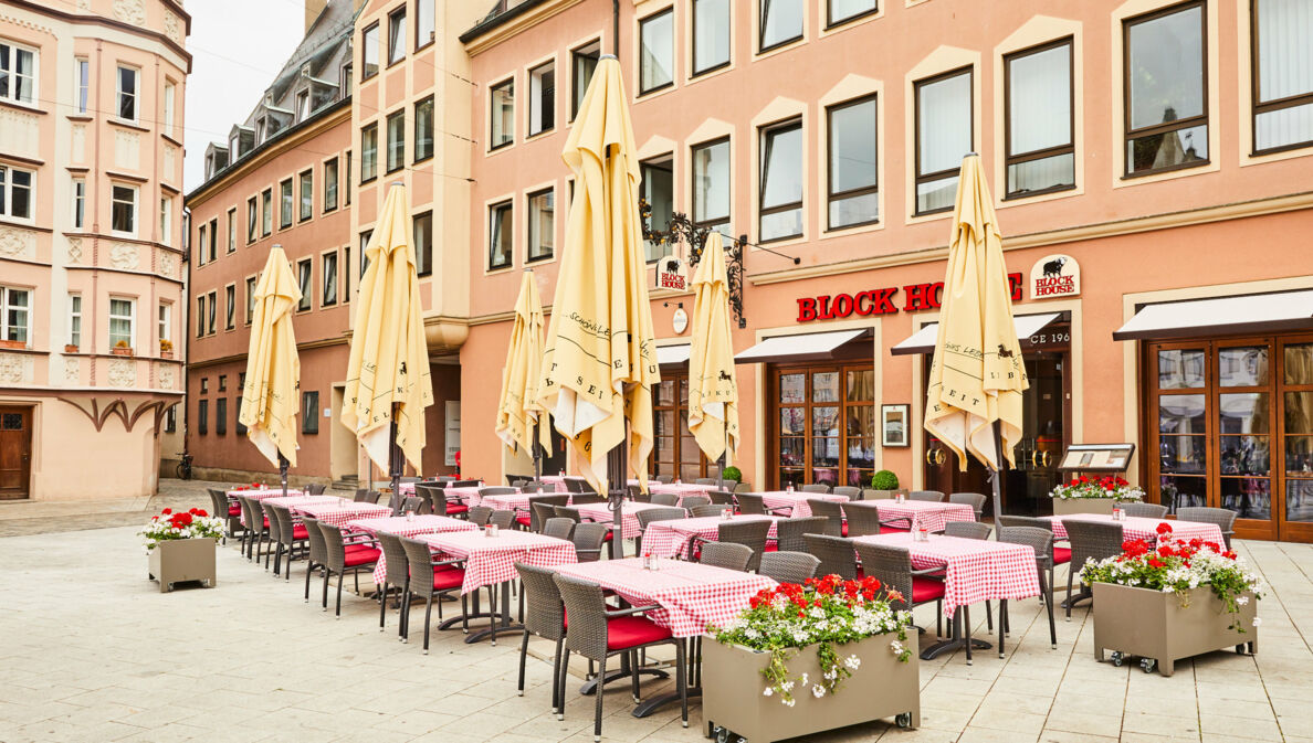 Block House Restaurant mit Außengastronomie auf einem Platz in einer Altstadt.