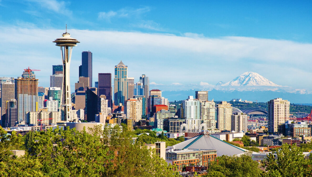 Skyline von Seattle mit Space Needle Turm vor schneebedeckter Bergspitze am Horizont.