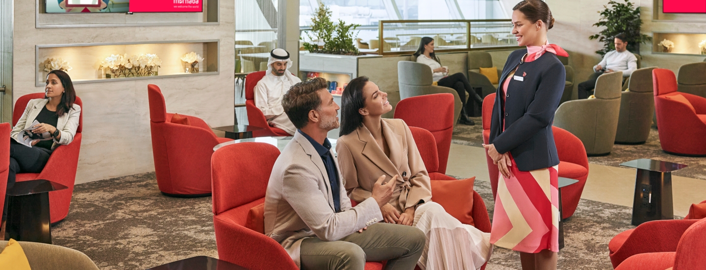 Mehrere Personen sitzen auf Polstermöbeln in einer modernen Flughafenlounge.