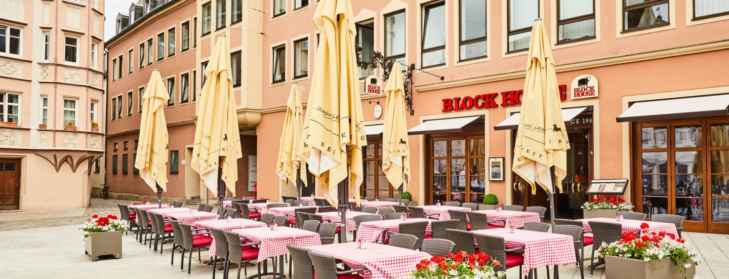 Block House Restaurant mit Außengastronomie auf einem Platz in einer Altstadt.