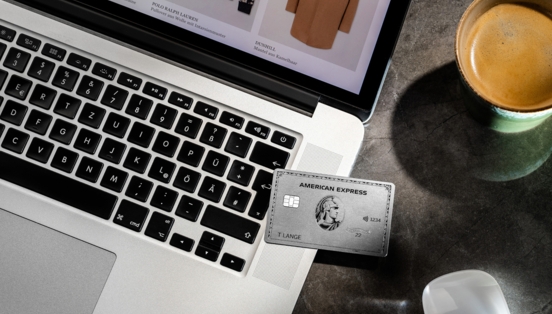 Eine silberne American Express Kreditkarte liegt auf einem Laptop beim Online-Shopping.