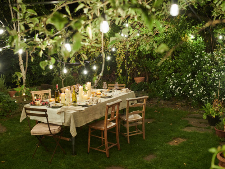 Ein gedeckter Tisch in einem Garten mit stimmungsvoller Beleuchtung bei Nacht