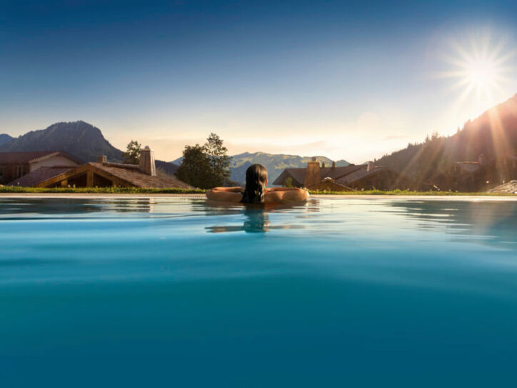 Rückansicht einer Person in einem Pool, im Hintergrund Berge