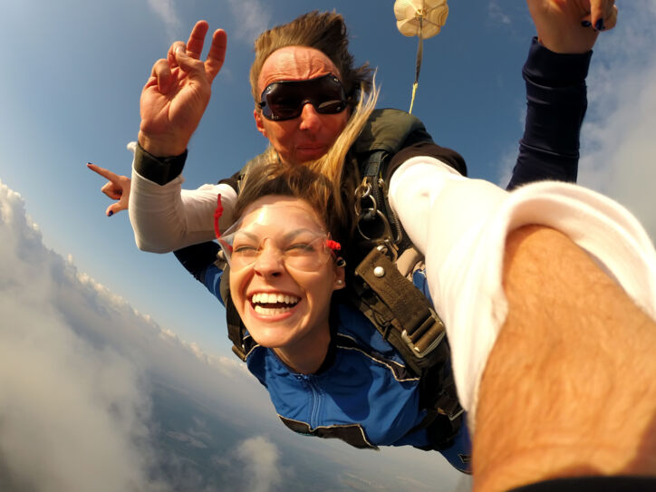 Ein Mann und eine fröhliche Frau beim Tandem-Fallschirmspringen.