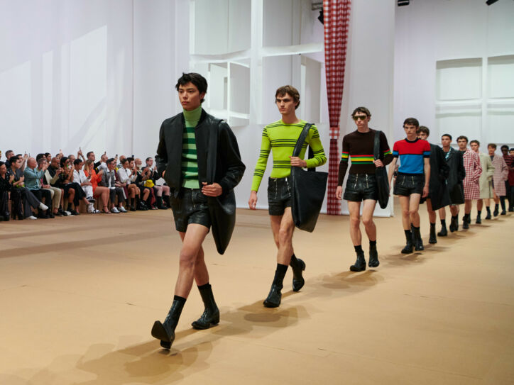 Männliche Models in Ledershorts laufen in Reihe auf einem Catwalk