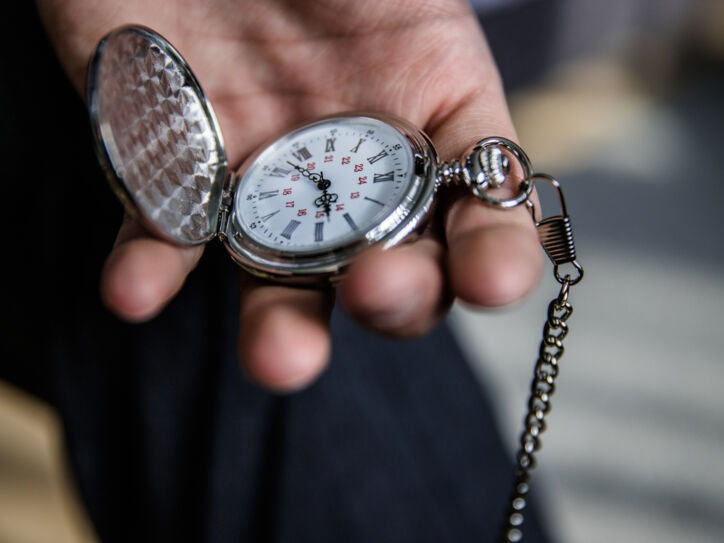 Eine Person hält eine aufgeklappte Taschenuhr in der Hand