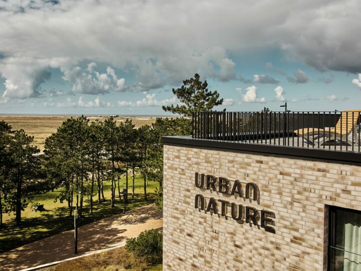 Blick auf die Dachterrasse des Urban Nature Hotels St. Peter Ording, im Hintergrund Bäume, Dünen, Meer und Wolken