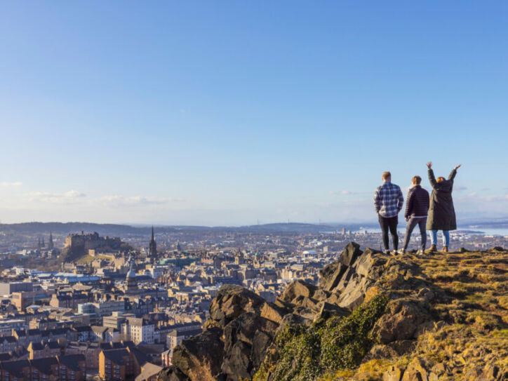 Drei Personen stehen auf einer Erhöhung und blicken von dort über Edinburgh