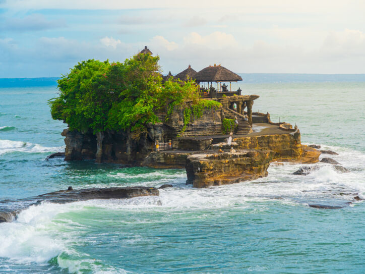 Ein Tempel und mehrere Bäume auf einem Felsen im Meer