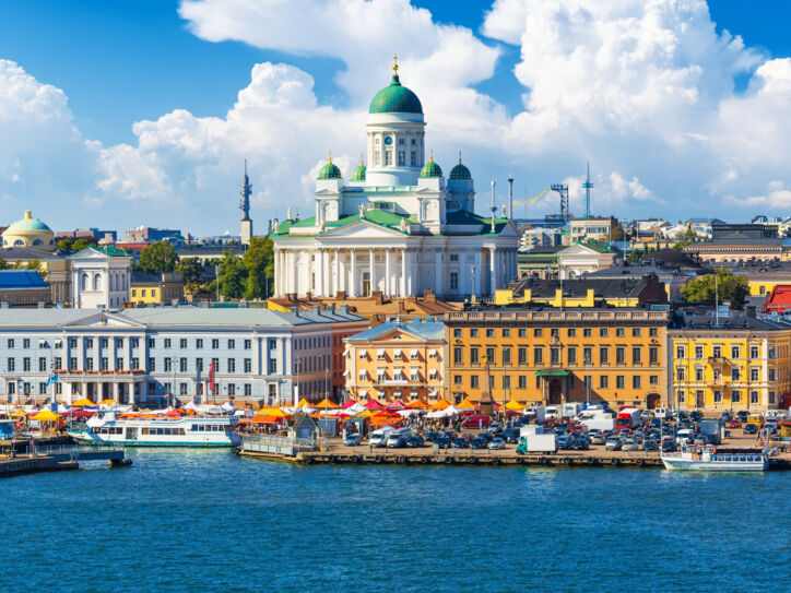 Blick auf eine Stadt am Wasser mit bunten Häusern und einer weißen Kathedrale im Mittelpunkt.