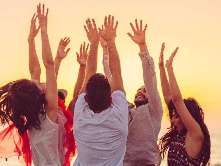 people dancing at the beach with hands up. concept about party, music and people