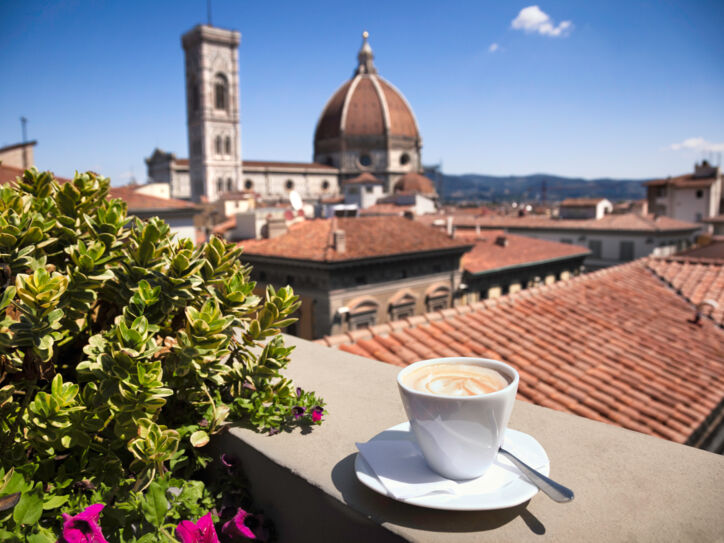 Stadtpanorama von Florenz mit Dom, im Vordergrund eine weiße Cappuccinotasse auf einer Mauer.