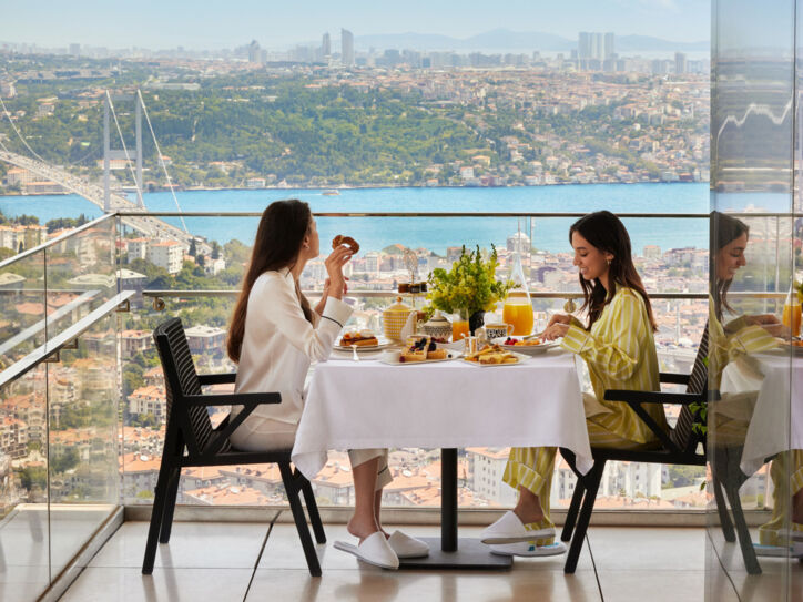 Zwei Frauen frühstücken an einem Tisch auf einem Balkon mit Aussicht auf Istanbul.