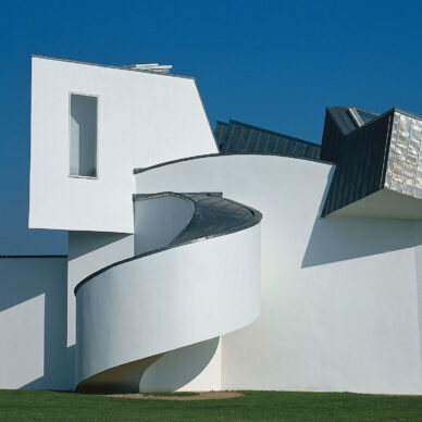 Ein weißes, architektonisch verspieltes Gebäude auf einer grünen Wiese.