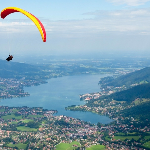 Gleitschirmflieger mit Blick von oben auf den Tegernsee