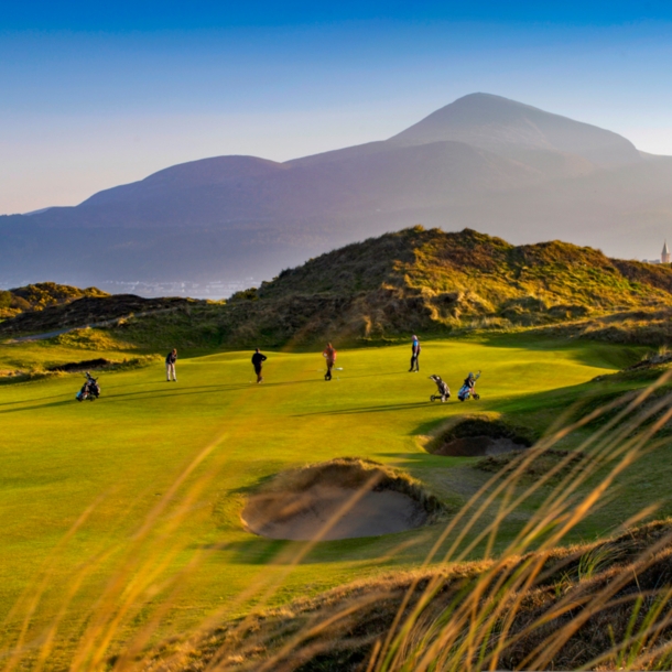 Vier Golfende während der Abenddämmerung auf einem Golfplatz